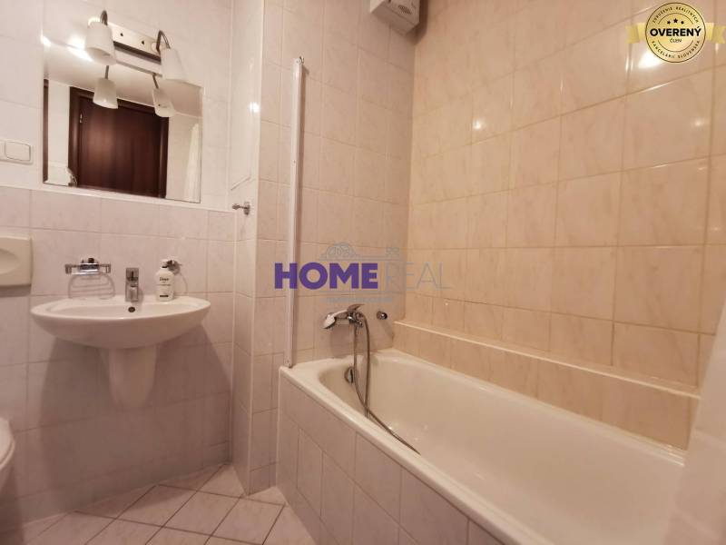 Badezimmer in einer 2-Zimmer-Wohnung mit Badewanne, Waschbecken und Spiegel.