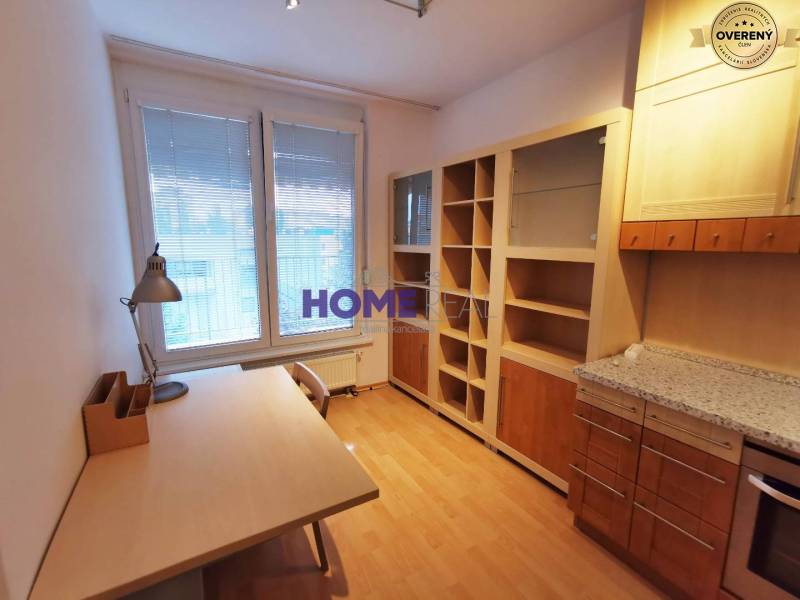 Ein Arbeitszimmer in einer 2-Zimmer-Wohnung mit einem Holzboden, einem Tisch und einem Bücherregal.