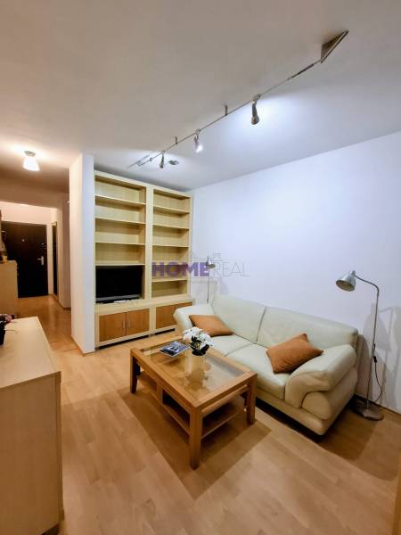 Wohnzimmer in einer Zweizimmerwohnung mit cremefarbenem Sofa und Holzboden.