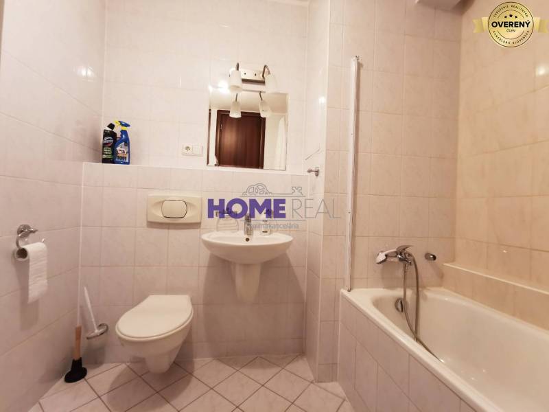 Badezimmer in einer 2-Zimmer-Wohnung mit Badewanne, Waschbecken und Toilette, gefliest mit weißen Fliesen.