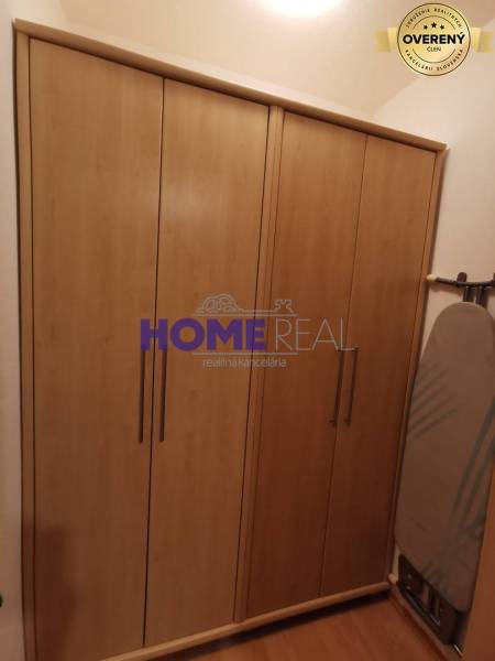 In einer 2-Zimmer-Wohnung sieht man einen Schrank mit Holzdekor und ein Bügelbrett.