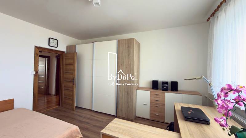 Schlafzimmer mit Holzboden, Einbauschrank und Pflanze in einer 3-Zimmer-Wohnung.