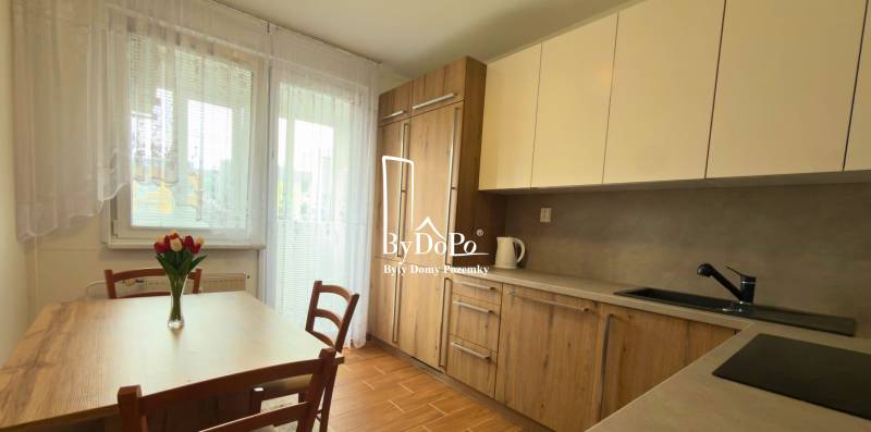 Küche in einer 3-Zimmer-Wohnung mit Holzdekor und hellem Möbeln, elegante Blumen auf dem Tisch.