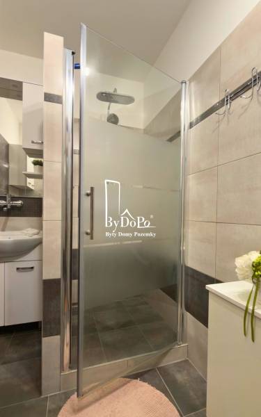 Duschkabine mit modernen Fliesen und Waschbecken in einer 3-Zimmer-Wohnung.