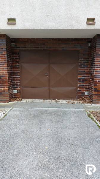 Garage vor dem Feld in Trenčín mit braunen Toren und Ziegelverkleidung, 3-Zimmer-Wohnung.
