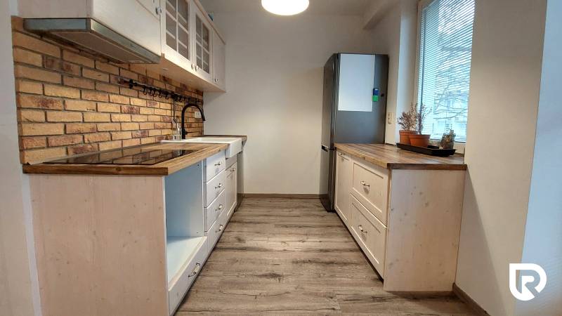 Küche in einer 3-Zimmer-Wohnung mit Holzboden und Ziegelverkleidung.