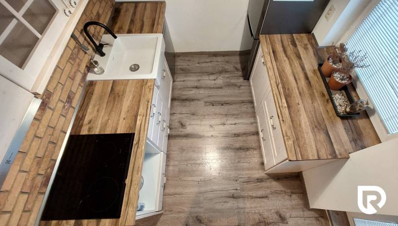 Küche in einer 3-Zimmer-Wohnung mit Holzboden und Küchenschränken.