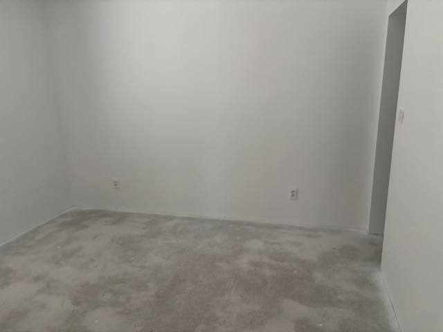 Ein Zimmer mit weißen Wänden und einem unauffälligen Teppich in einem Einfamilienhaus.