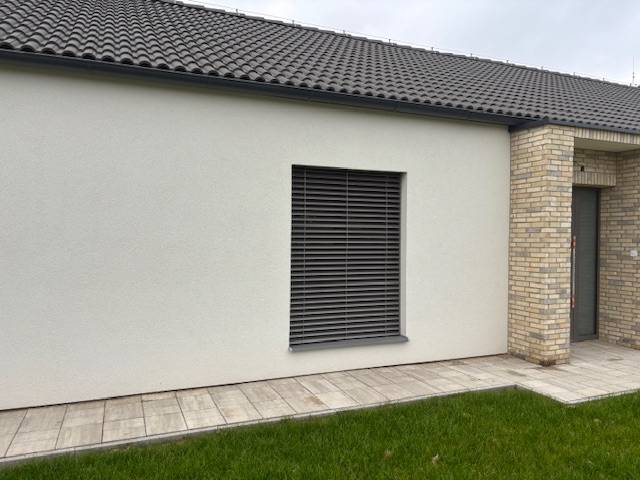 Das Äußere des Einfamilienhauses in der Fialkova-Straße in Tomášov mit Ziegelverkleidung und Rasen.