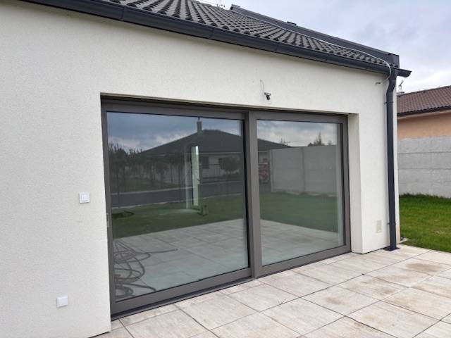 Ein Einfamilienhaus in Tomášov in der Fialkova-Straße mit Schiebetüren und einer Terrasse.