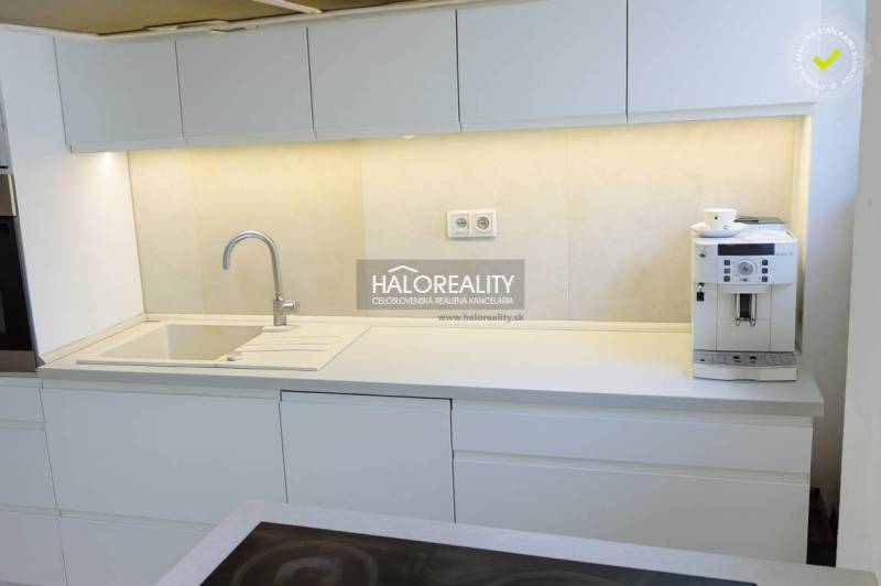 Eine Küche mit weißen Schränken und einer Kaffeemaschine in einer 3-Zimmer-Wohnung.