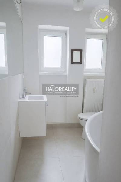 Badezimmer in einer 3-Zimmer-Wohnung mit weißem Waschbecken, Badewanne und Heizkörper.