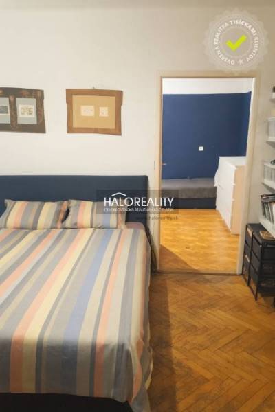 Schlafzimmer in einer 3-Zimmer-Wohnung mit Holzboden und bunter Bettwäsche.