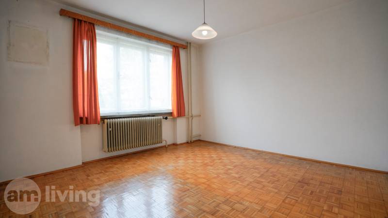 Ein Zimmer mit einem Holzboden, weißen Wänden und orangen Vorhängen in einem Einfamilienhaus.