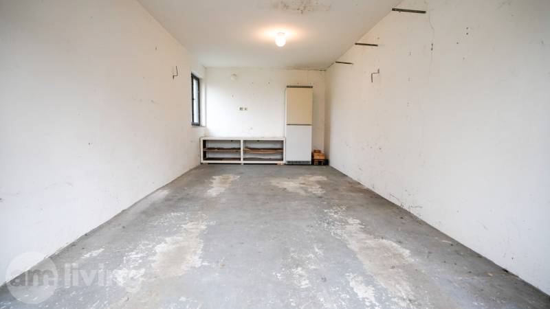 Garage in einem Einfamilienhaus mit Betonboden und weißen Wänden.