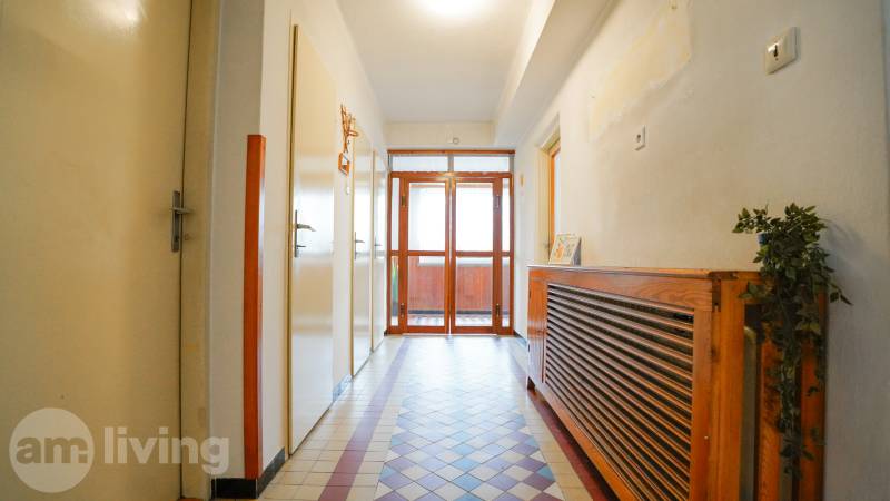 Flur in einem Einfamilienhaus mit Fliesenboden und einem hölzernen Heizkörperverkleidung.