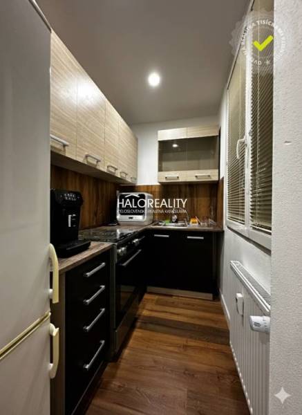 Küche in einer Einzimmerwohnung mit Holzboden und dunklen Schränken.