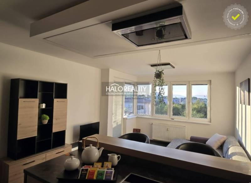 Wohnzimmer in einer Zweizimmerwohnung mit hellen Wänden und Fenstern, möbliert.