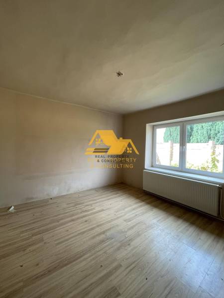 Ein Zimmer mit einem Holzboden und einem großen Fenster in einem Einfamilienhaus.