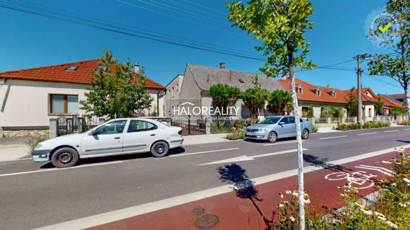 Eine Straße in Malacky mit Einfamilienhäusern, geparkten Autos und einem Fahrradstreifen.