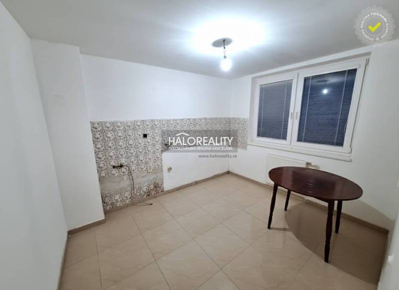 Ein Zimmer in einem Einfamilienhaus mit weißen Wänden, einem Fenster und Fliesen.