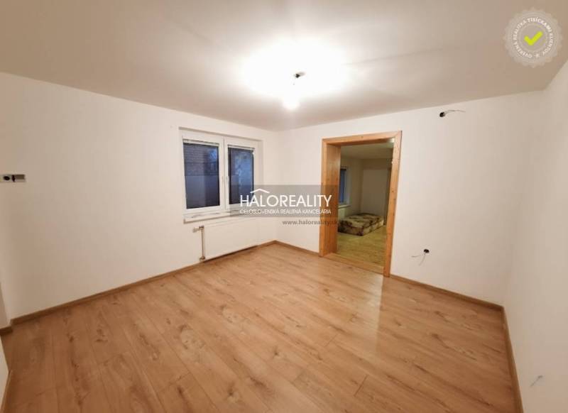 Ein Zimmer in einem Einfamilienhaus mit einem Boden in Holzoptik und weißen Wänden.