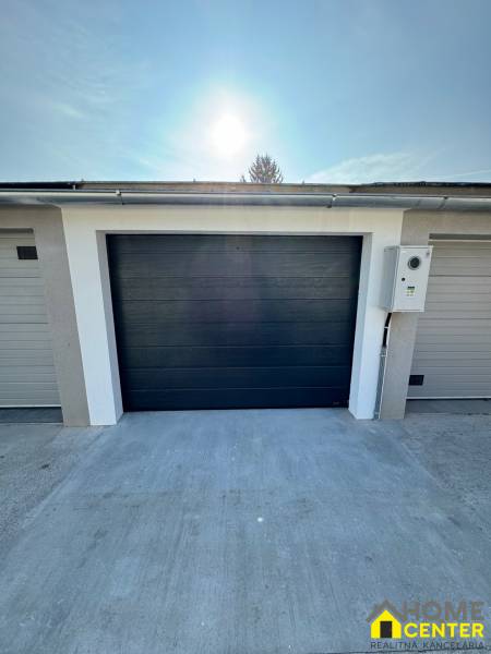 Garagen in der Slnečná-Straße in Komárno mit dunklen Toren und Betonfläche.