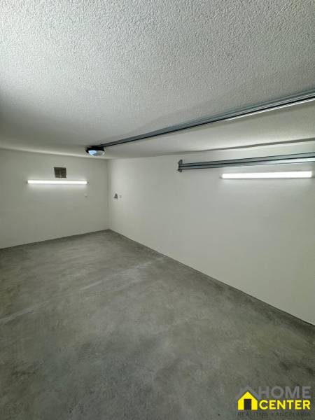 Innenraum einer Garage mit Betonboden und Beleuchtung im Garagenbereich.