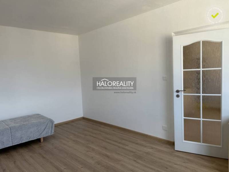 Ein Zimmer in einer Einzimmerwohnung mit einem Boden in Holzoptik und weißen Wänden.