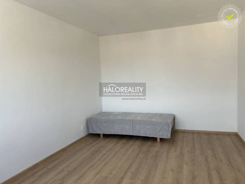 Einfaches Zimmer in einer Einzimmerwohnung mit Bett und Holzboden.