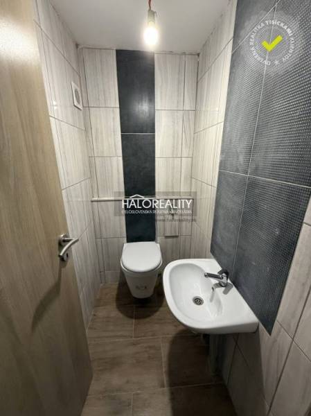 Toilette mit Waschbecken in einem Einfamilienhaus, geflieste Wände, Boden mit Holzdekor.