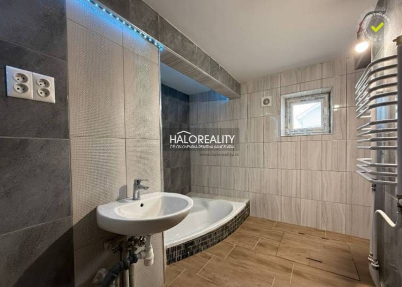 Badezimmer eines Einfamilienhauses mit Badewanne, Waschbecken und Boden mit Holzdekor.