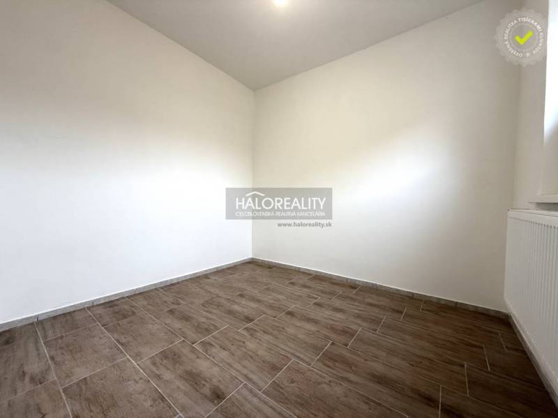 Ein Zimmer mit Holzboden in einem Einfamilienhaus, helle Wände, Heizkörper.