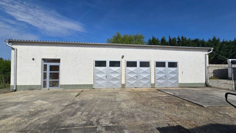 Weißes Gebäude mit vier Metalltoren und Eingang in Šaľa, geeignet für Lager und Hallen.