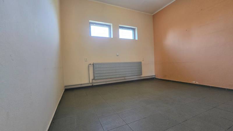 Innenraum von Lagern und Hallen mit Fliesenboden und Heizkörper unter einem Paar Fenstern.