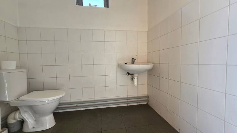 Toilette in Lagerhäusern und Hallen mit weißen Fliesen und kleinem Fenster.