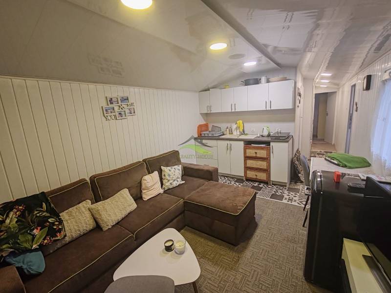 Wohnzimmer in einer Hütte mit bequemer Couch, Küchenzeile und dekorativem Wandbelag.