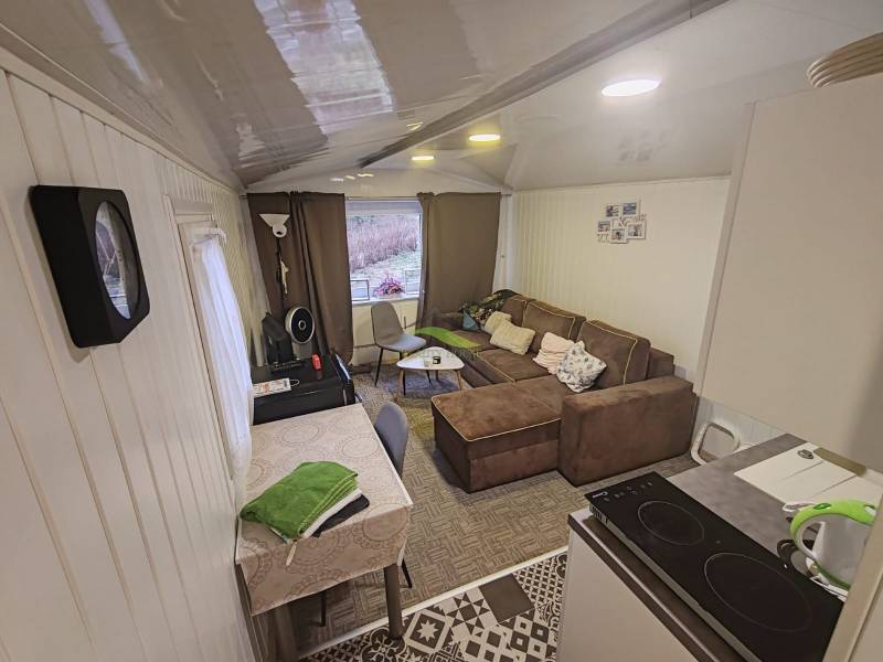 Interieur der Hütte mit Sofa, Esstisch und ausgestatteter Küche.