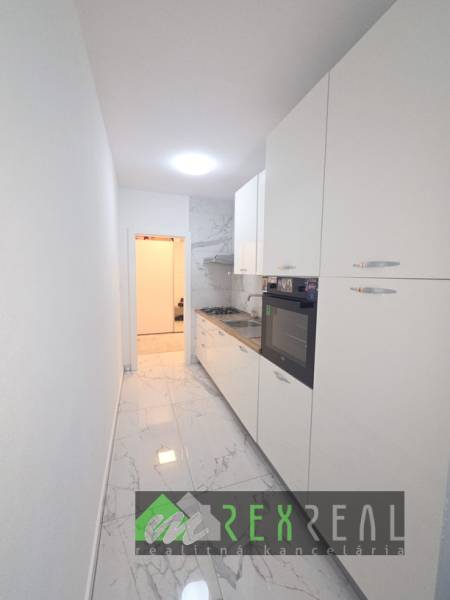 Schmale weiße Küche mit Kochfeld und Ofen, Marmorboden in einer 3-Zimmer-Wohnung.