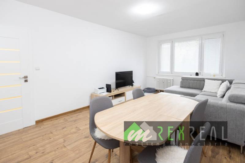 Wohnzimmer in einer 3-Zimmer-Wohnung mit Holzboden und grauem Sofa.