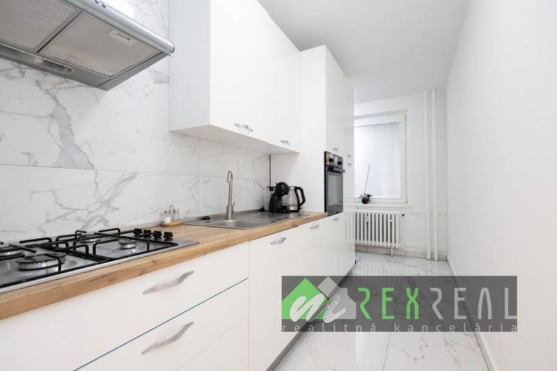 Küche mit weißen Schränken, Marmorboden und eingebauten Geräten in einer 3-Zimmer-Wohnung.