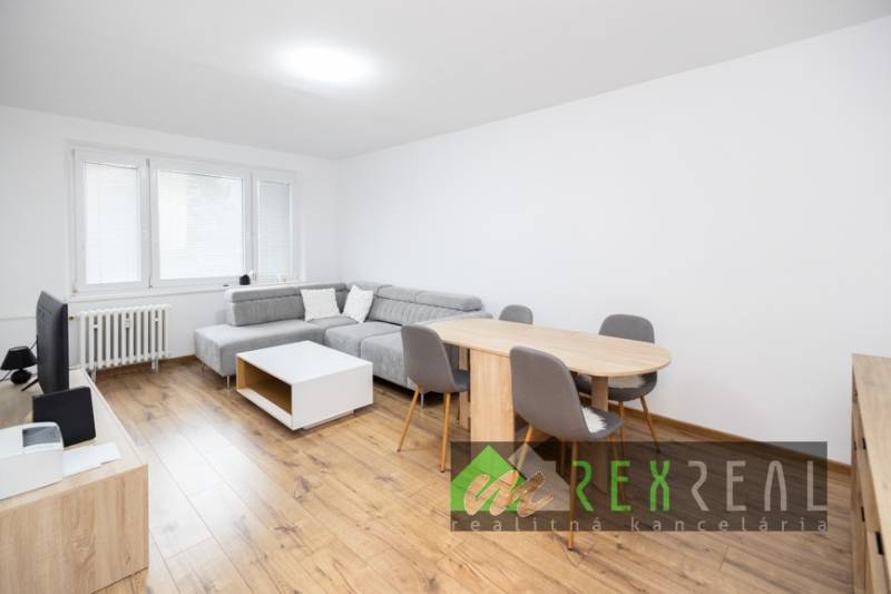 Wohnzimmer in einer 3-Zimmer-Wohnung mit Holzboden, grauem Sofa und Esstisch.
