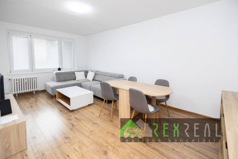 Wohnzimmer mit Ecksofa, Esstisch und Boden in Holzoptik.