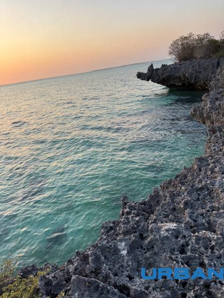Küstenklippen und Sonnenuntergang über sanften Meereswellen in Kizimkazi, Grundstücke - Gewerbe.