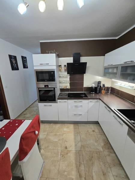 Küche in einer 3-Zimmer-Wohnung mit Leuchten, weißen Schränken und Fliesen.