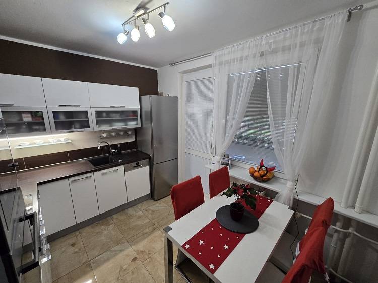 Küche in einer 3-Zimmer-Wohnung mit weißen Möbeln, Esstisch und Holzboden.