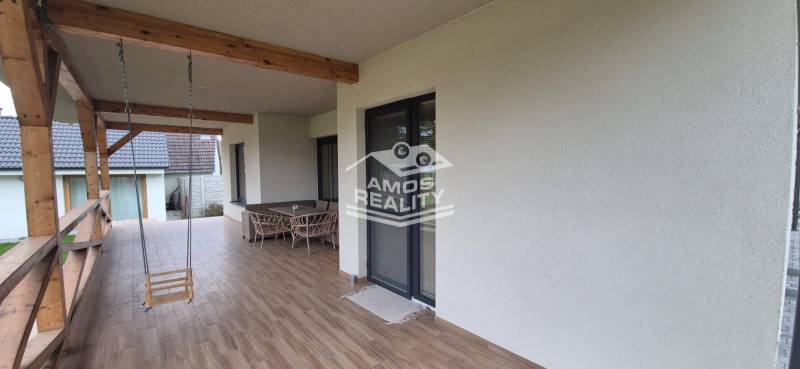 Die Terrasse des Einfamilienhauses in Studienka mit einer Schaukel und Möbeln, Boden mit Holzdekor.