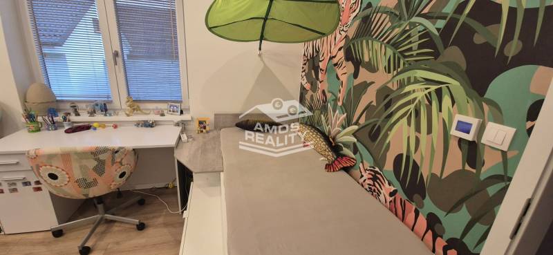 Kinderzimmer mit Schreibtisch und bunter Tapete mit Motiven in einem Einfamilienhaus.