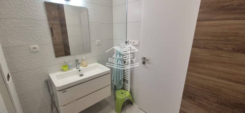 Badezimmer in einem Einfamilienhaus mit Waschbecken, Relief-Fliesen, Spiegel und beleuchteten Wänden.