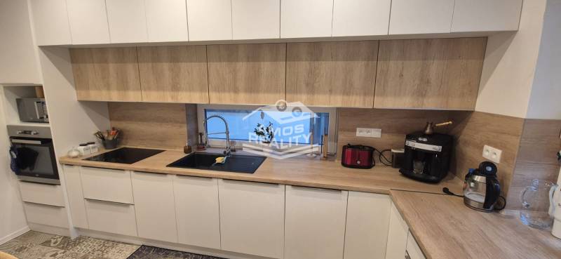 Küche in einem Einfamilienhaus mit weißen Schränken und einer Arbeitsplatte in Holzoptik.